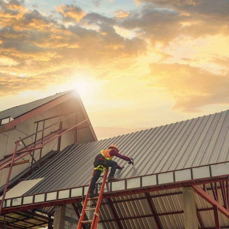 sunset of roof - man working on ladder on roof roof services - bristol - south west